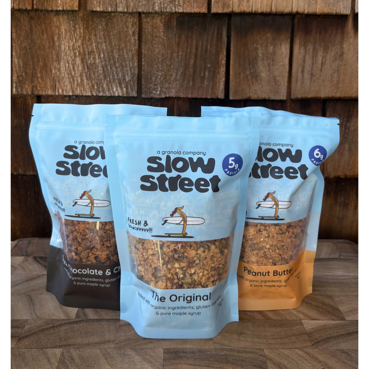 Slow Street granola mixed-flavor bundle: Original in front, Dark Chocolate and Cherry left, Peanut Butter right.