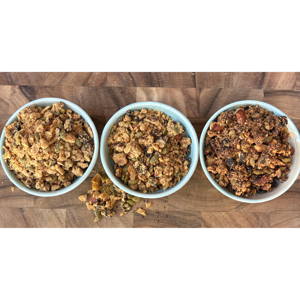 Three bowls of Slow Street granola on a wooden board, without product bags.